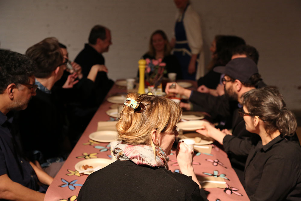 image from the March 7, 2026 edition of Saturday Salons. audience members sit at a long table covered in hand-decorated craft paper.
