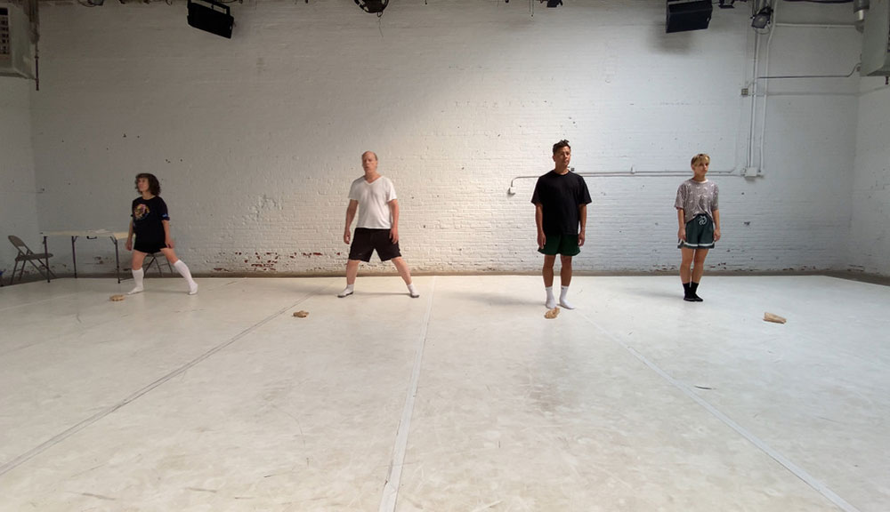 rehearsal image (by Dayna Hanson) from Hugely Amplified Present. Heather Kravas, Jim Fletcher, Jim Kent, and Julia Sloane stand atop The Chocolate Factory's white Marley floor, facing the camera.